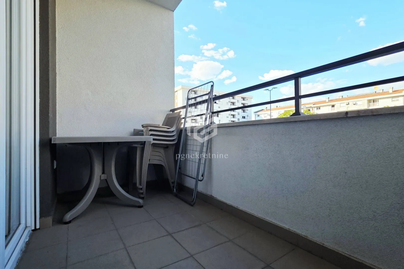 Natkriveni balkon sa stolom, stolicama i sušačem za veš.