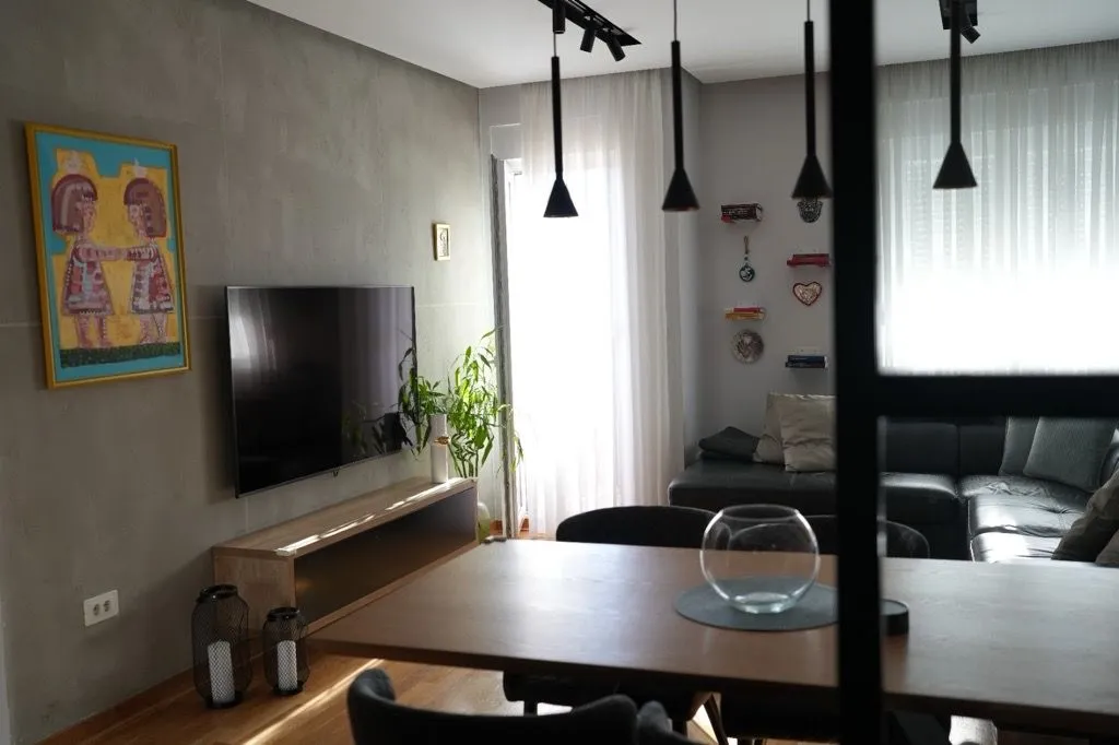 Living room with dining area, sofa, and TV.