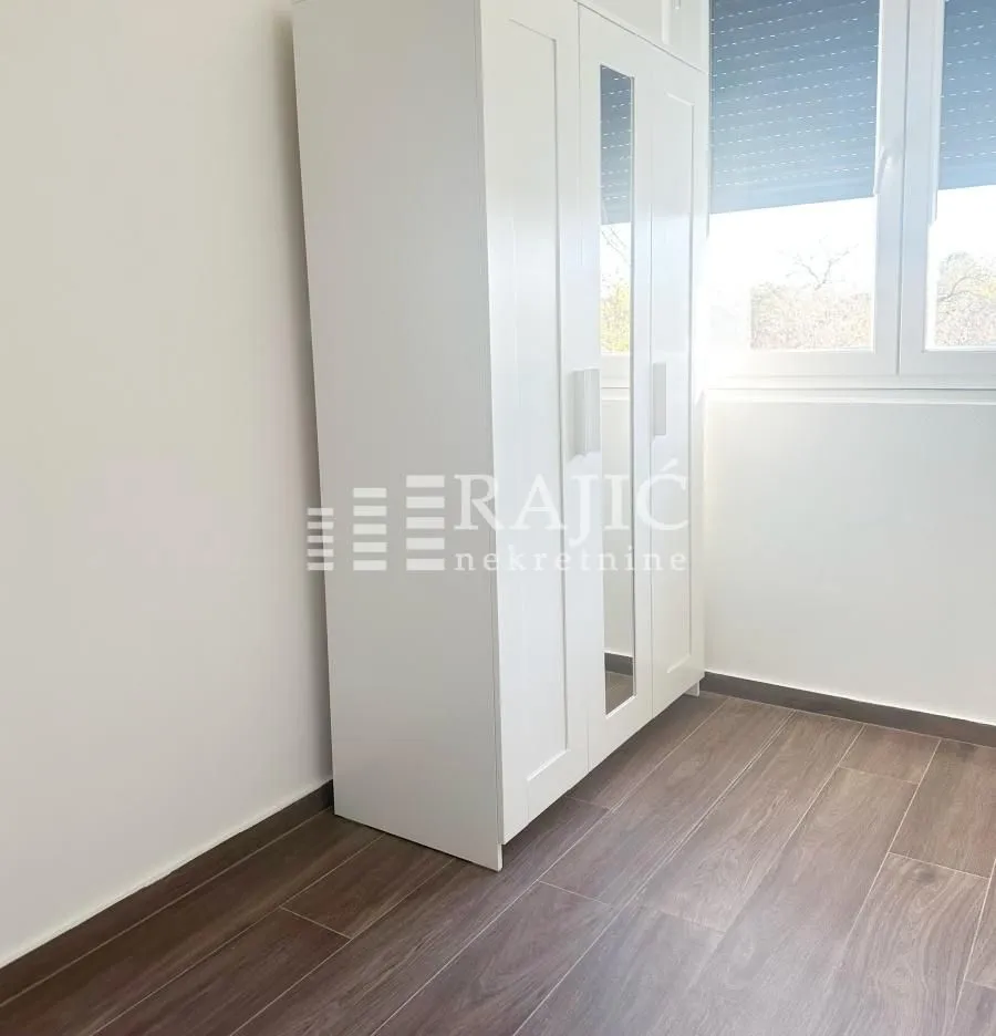 Bright bedroom with a white wardrobe and laminate flooring.