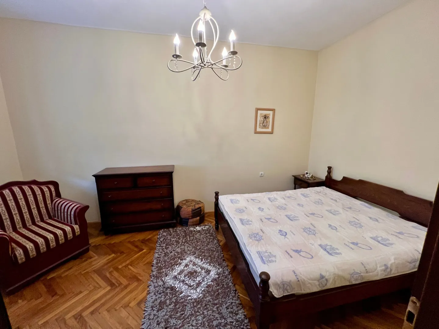 Bedroom with a double bed, armchair, and parquet flooring.