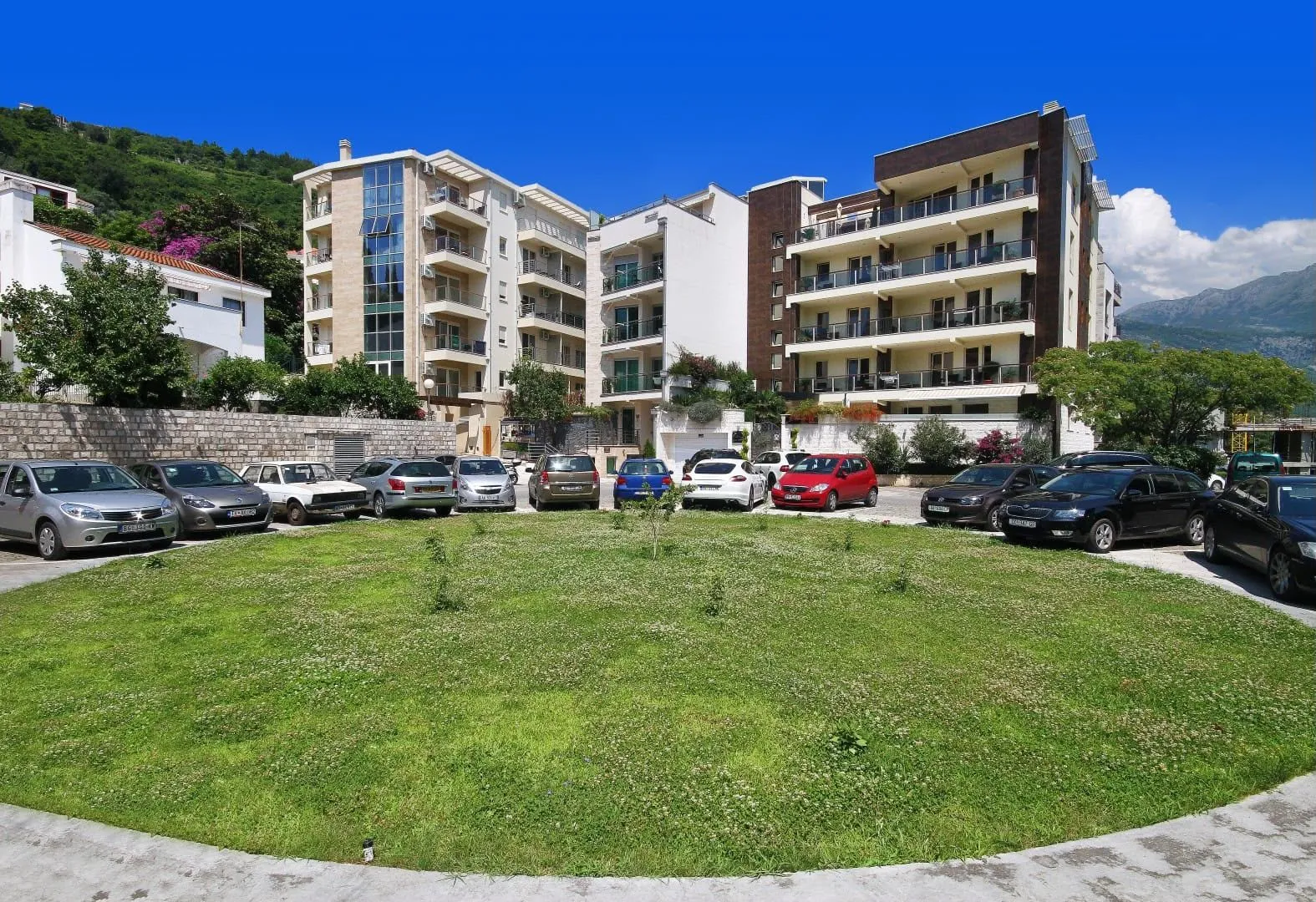 Exterior view of apartment buildings with a landscaped lawn and parking lot in the foreground.