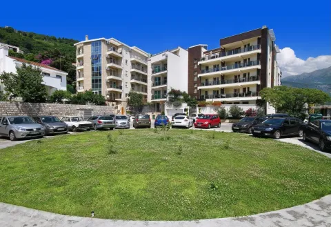 Exterior view of apartment buildings with a landscaped lawn and parking lot in the foreground. - image 16