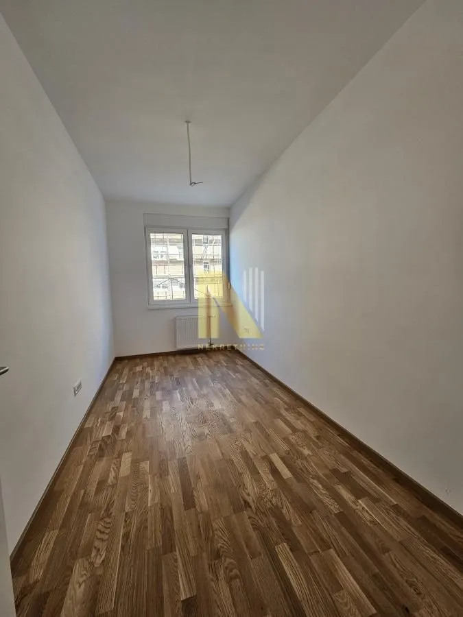 Prazna soba sa parketom i prozorom.