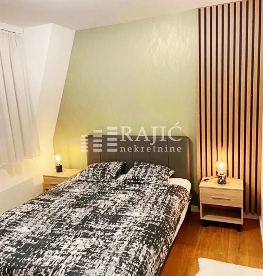 Furnished bedroom with a double bed and decorative wooden panels.