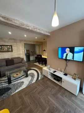 Prostrana dnevna soba sa garniturom i TV-om povezana sa trpezarijom. - image 3