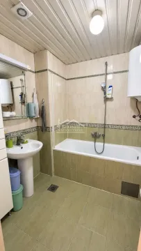 Kupatilo obloženo keramičkim pločicama sa kadom i umivaonikom. - image 11