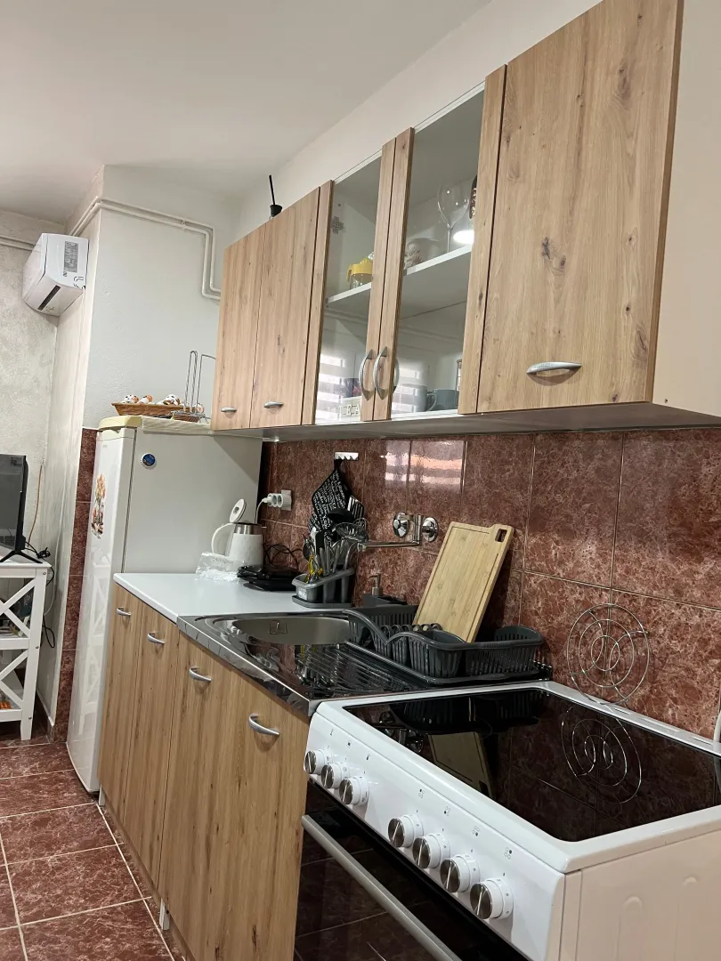 Small kitchen with wooden cabinets, stove, and refrigerator.