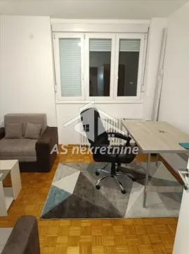 Small room with a desk, armchair, and parquet flooring. - image 12