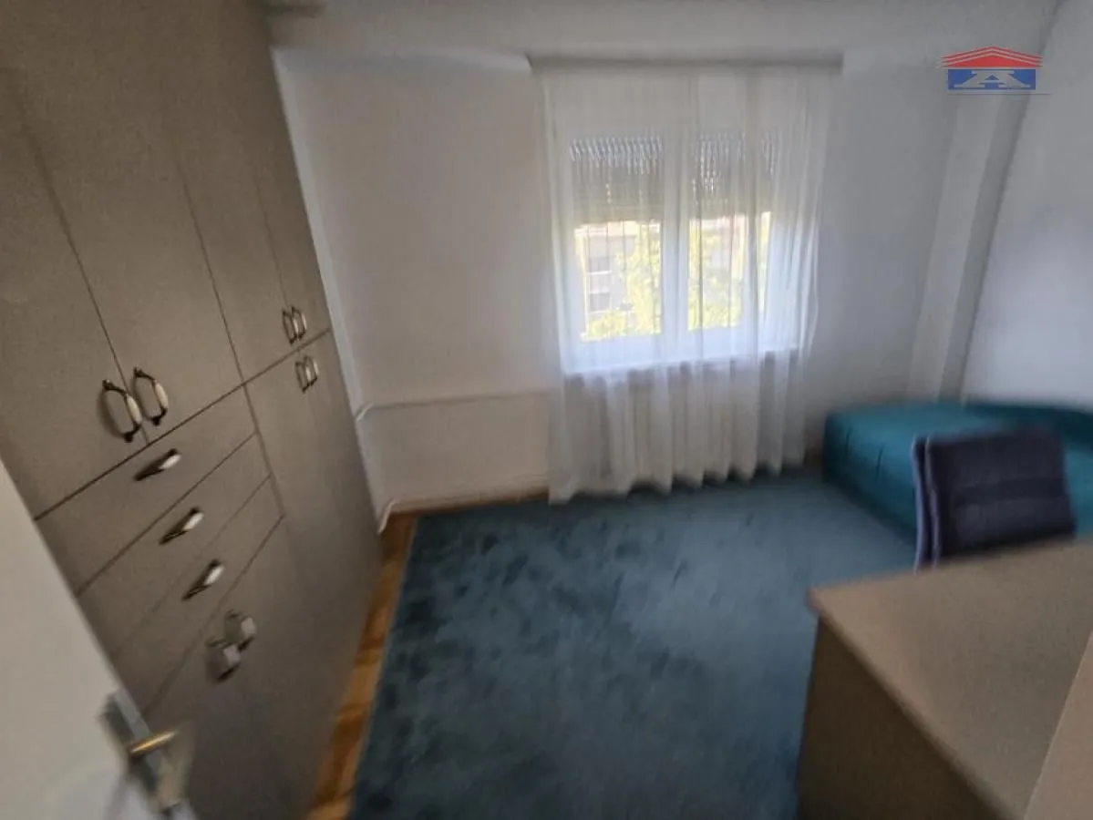 Small bedroom with a built-in wardrobe, bed, and a window with curtains.