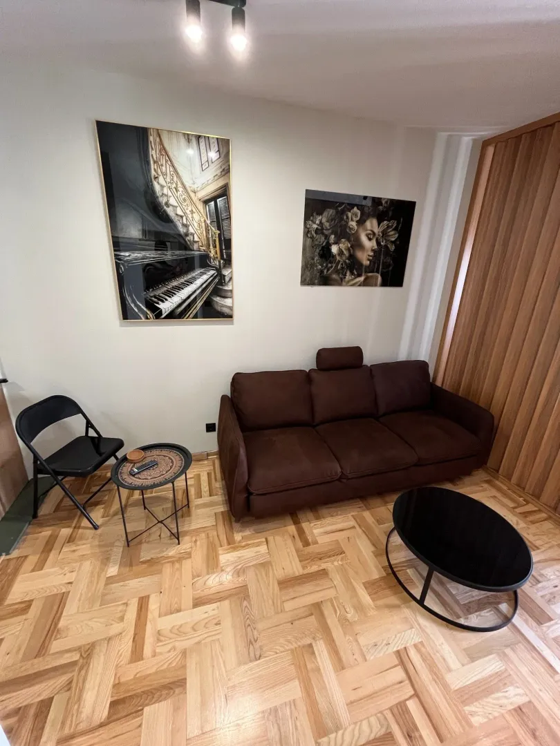 Dnevna soba sa braon trosjedom, parketom i umjetničkim slikama na zidu.
