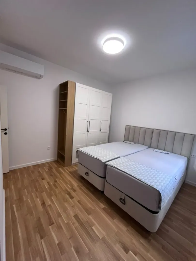 Svjetla spavaća soba sa dva kreveta i bijelim garderoberom.