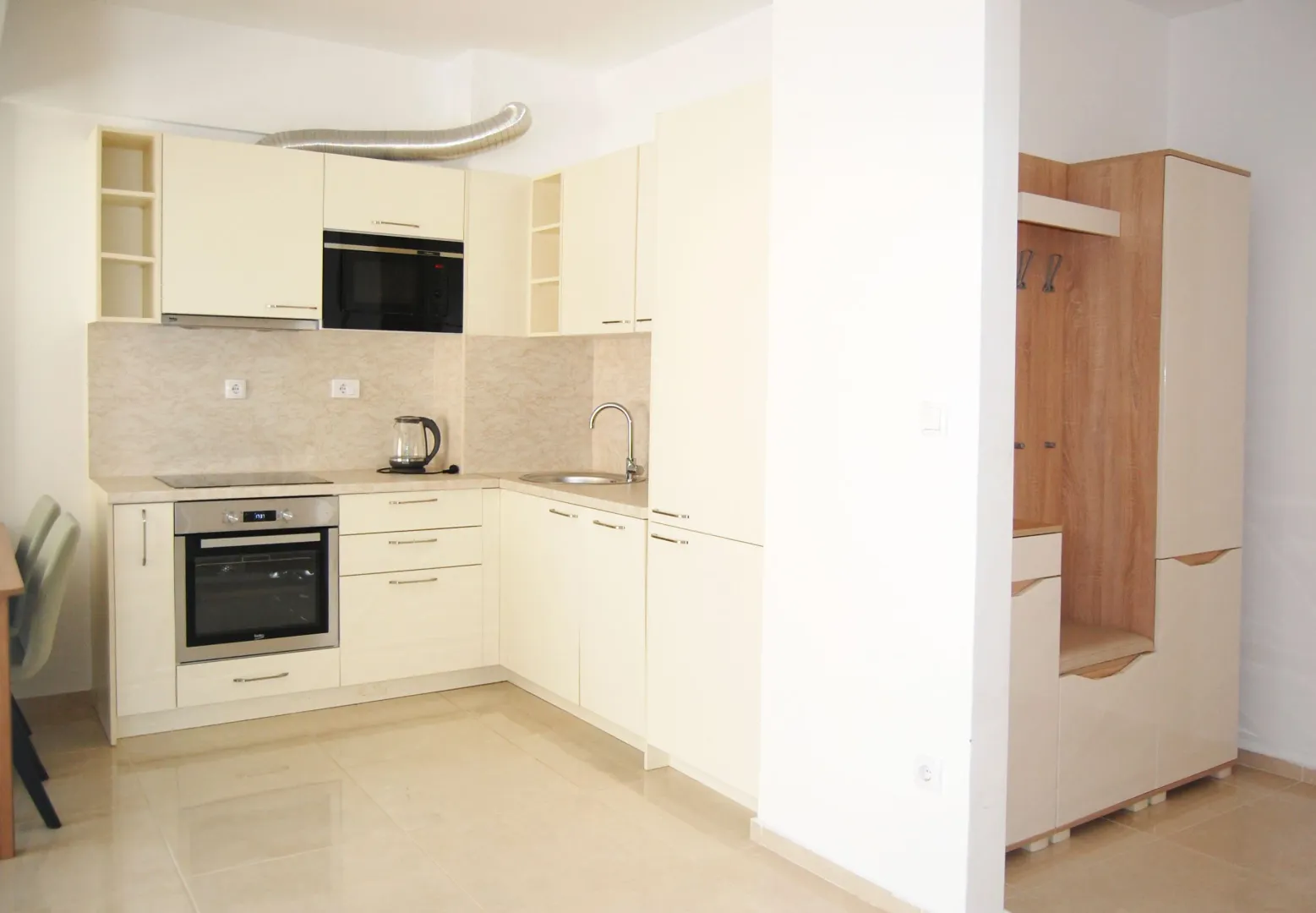 Modern kitchen in light tones with built-in appliances and a dining area.