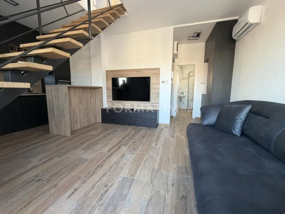 Living room with a sofa, TV, and stairs.