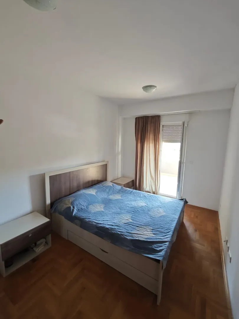 Spavaća soba sa bračnim krevetom, noćnim stočićem i izlazom na terasu.