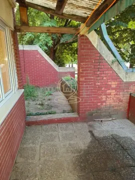 Natkrivena terasa sa popločanim podom i pogledom na deo dvorišta. - image 10