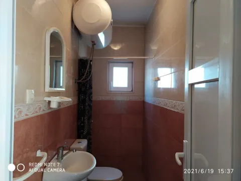 Smaller bathroom tiled with ceramic tiles featuring a sink and a water heater. - image 5