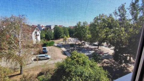 Pogled kroz prozor sa mrežicom na okolno zelenilo i zgrade. - image 20