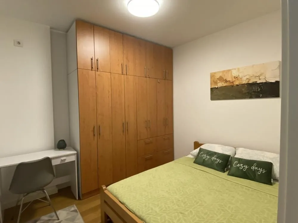 Furnished bedroom with a large wooden wardrobe and a desk.