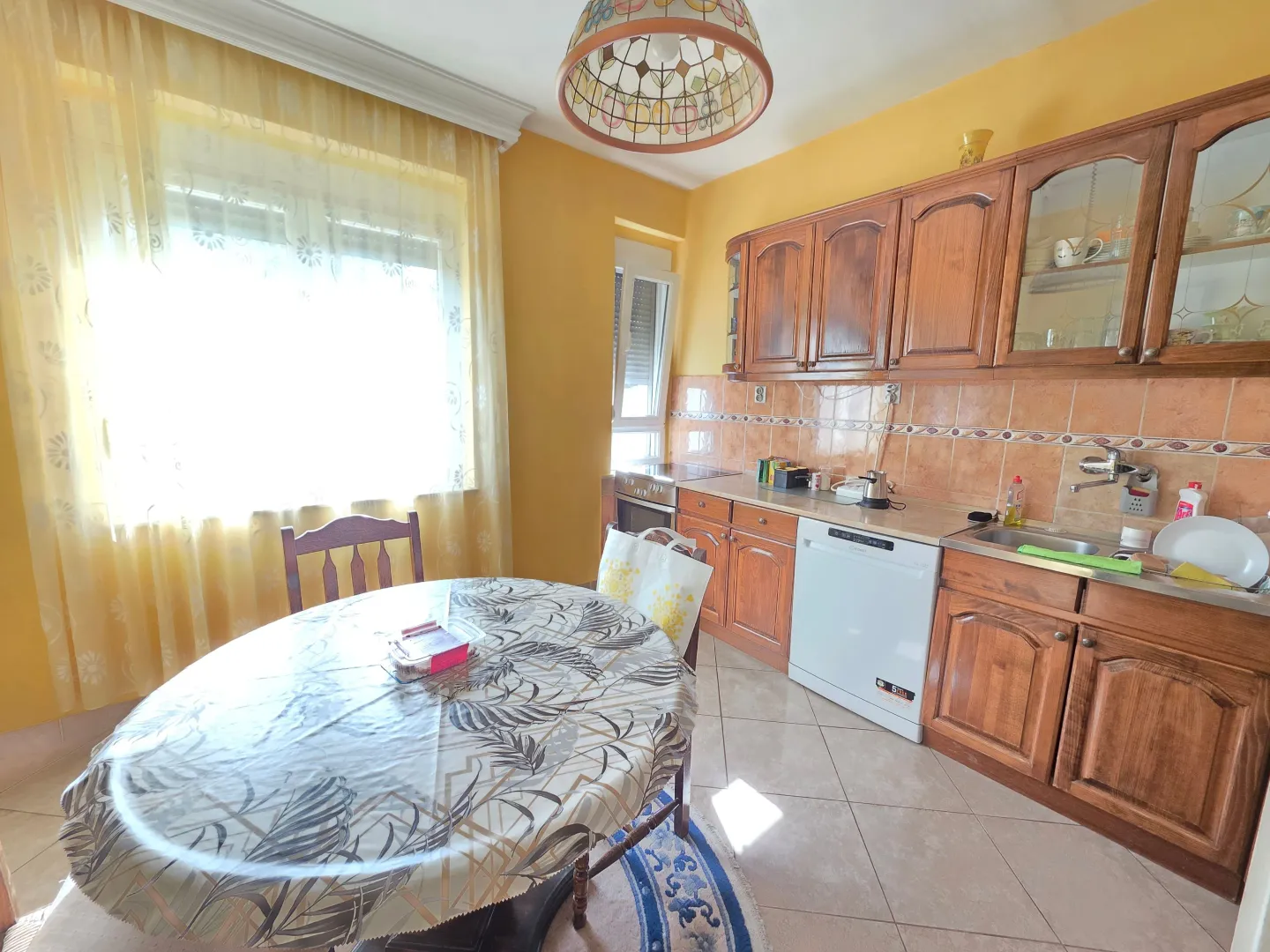 Kitchen with wooden cabinetry and a dining table by the window.