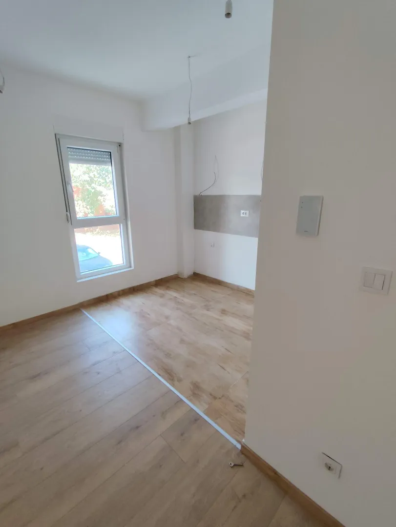 Empty room with wooden flooring and a single window.