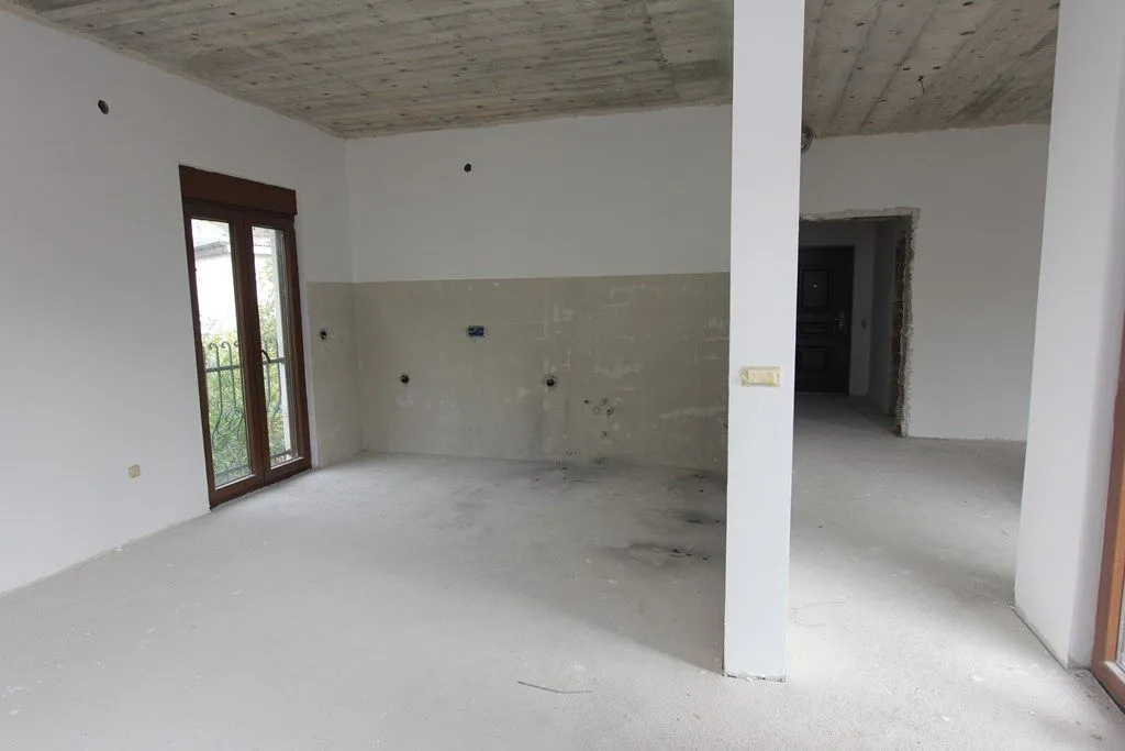 Prostrana prostorija u sivoj fazi gradnje sa betonskom tavanicom.