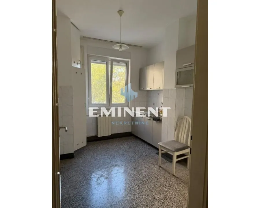 Empty kitchen with white cabinetry and a window.