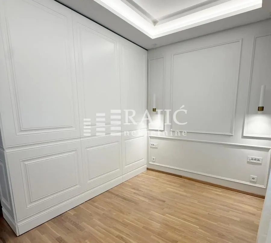 Modern bedroom with built-in wardrobe and decorative wall moldings.
