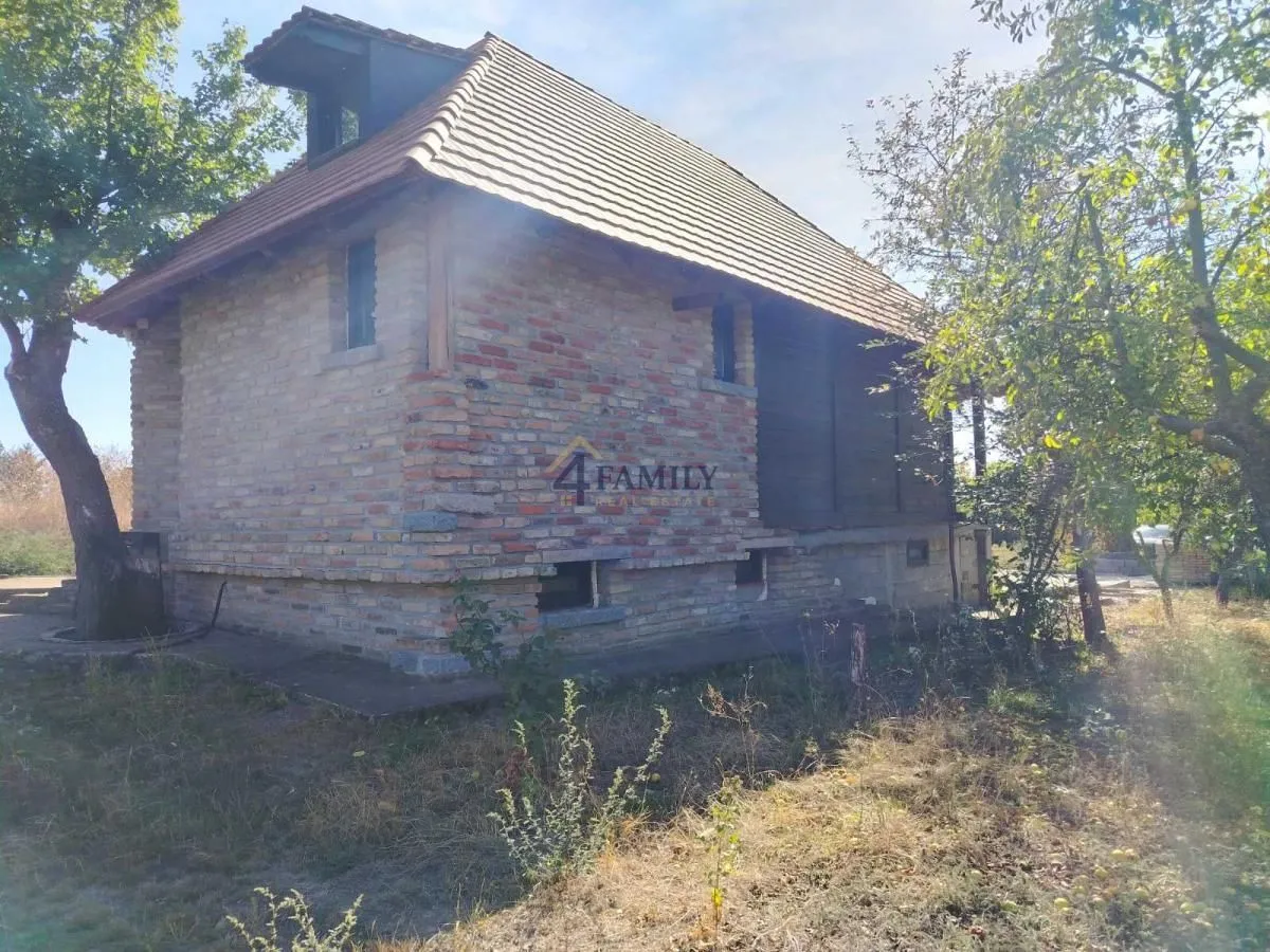 Eksterijer starije kuće od cigle okružene zelenilom.