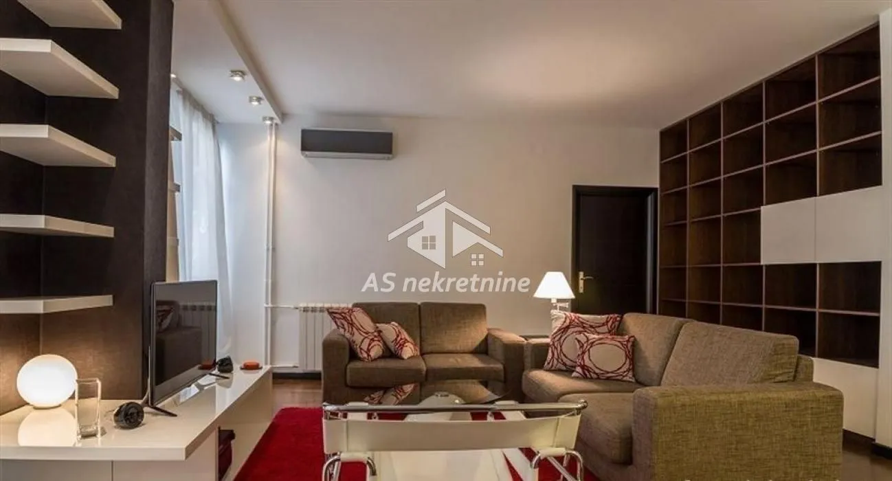 Living room with a sofa set, TV unit, and a large bookshelf.