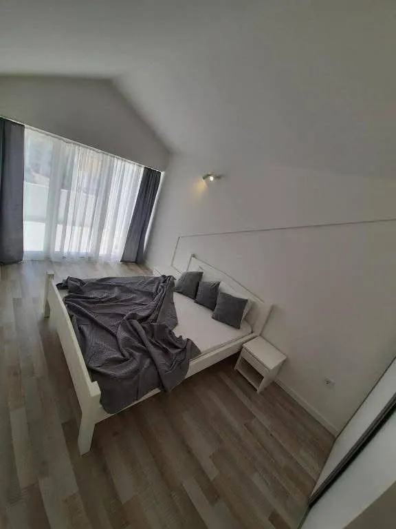 Svjetla spavaća soba sa bijelim krevetom i velikim prozorom.