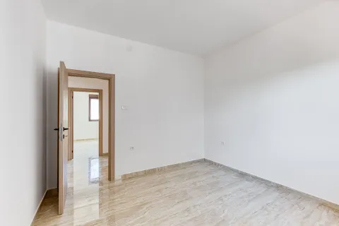 Prazna soba sa bijelim zidovima, keramičkim podom i drvenim vratima. - image 16