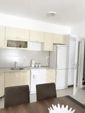 Kuhinja sa svijetlim elementima i trpezarijskim stolom u prvom planu. - image 4