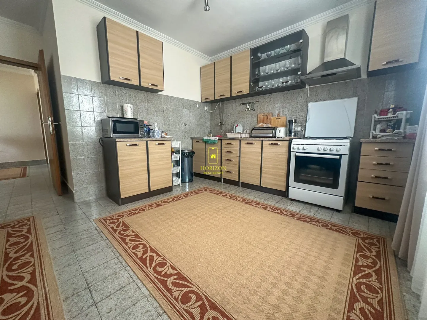 Potpuno opremljena kuhinja sa drvenim elementima i šporetom.