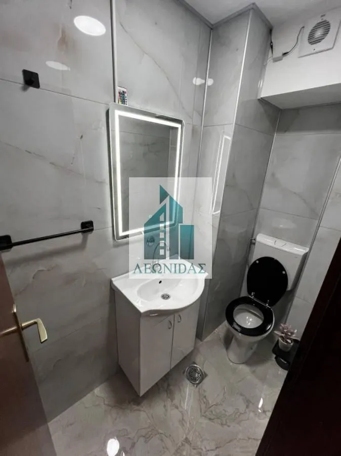 Modernly equipped bathroom with a washbasin, illuminated mirror, and toilet.