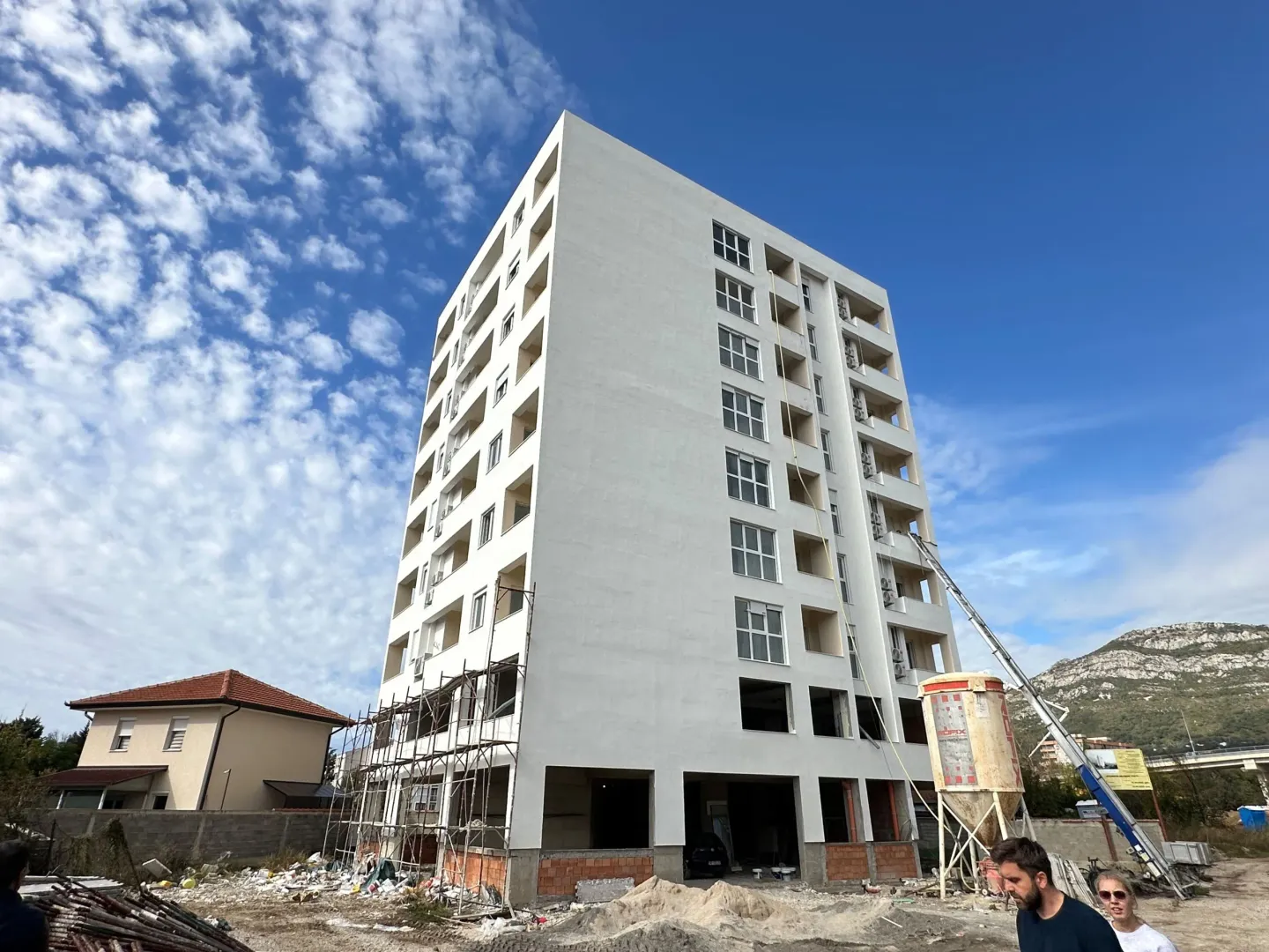 View of a multi-story building under construction with scaffolding and a blue sky.