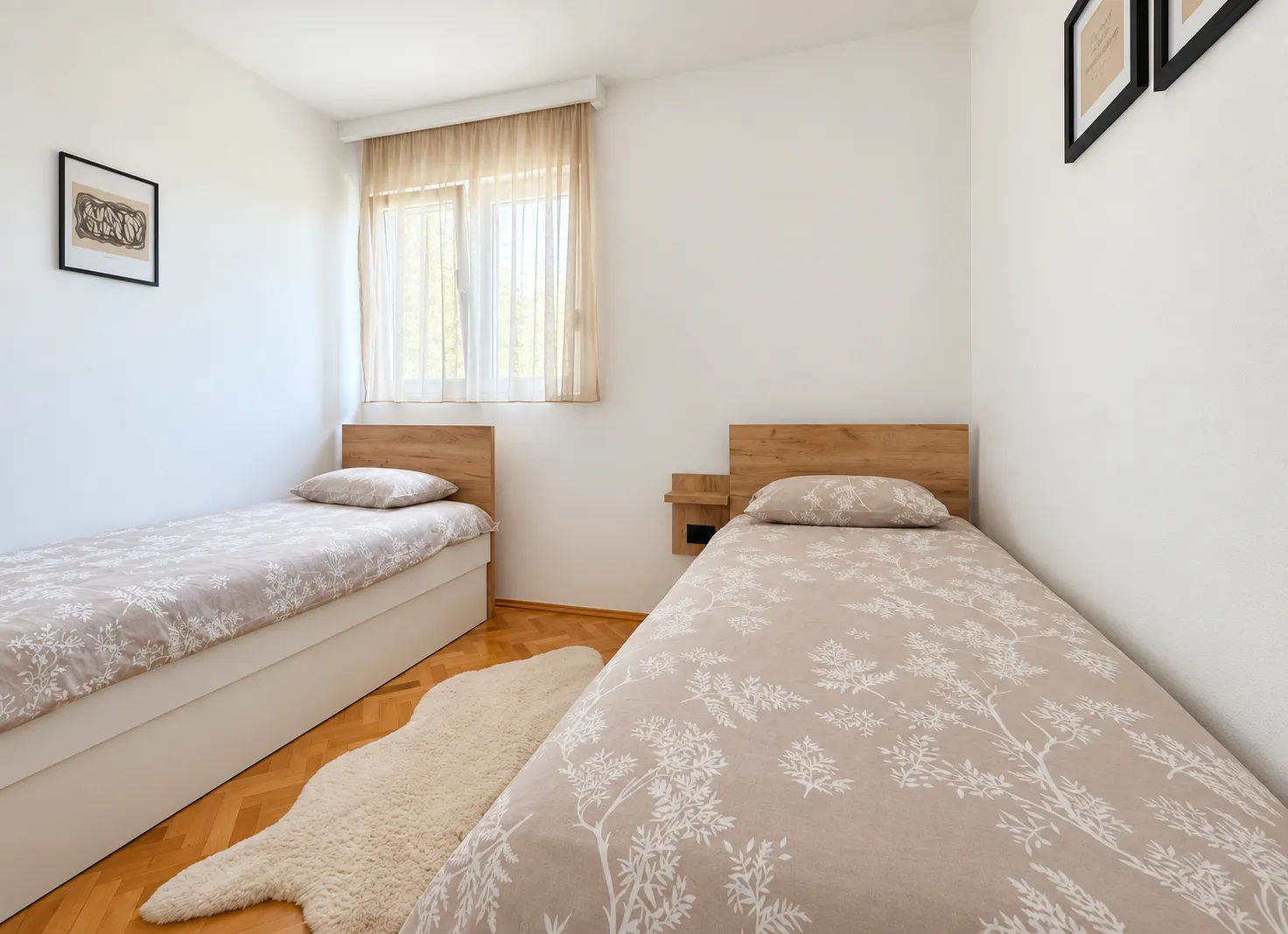 Bright bedroom with two single beds and wooden flooring.