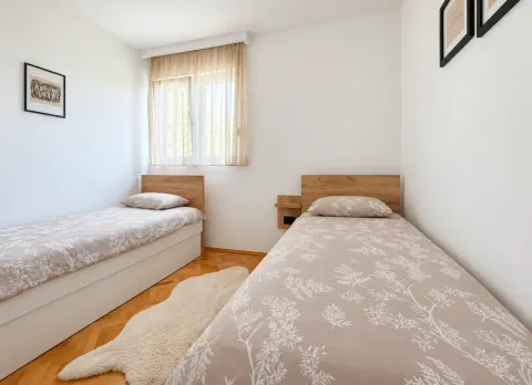 Bright bedroom with two single beds and wooden flooring. - image 3