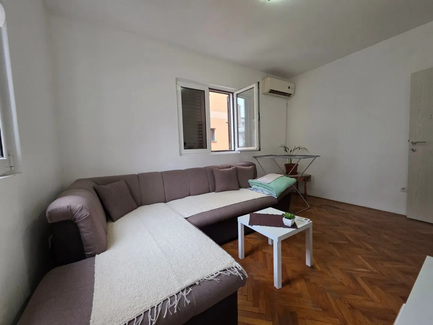 Living room with a sectional sofa, a small coffee table, and parquet flooring.