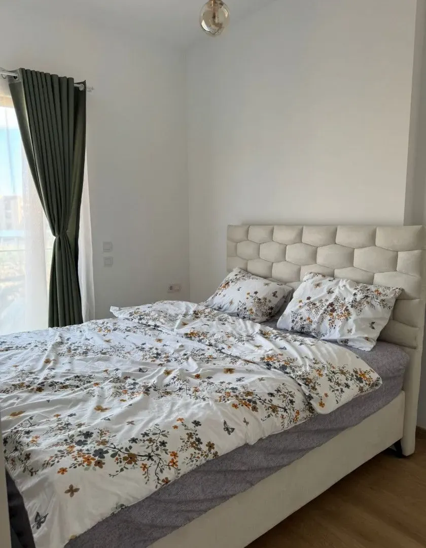 Bright and tidy bedroom with a large double bed and curtains.