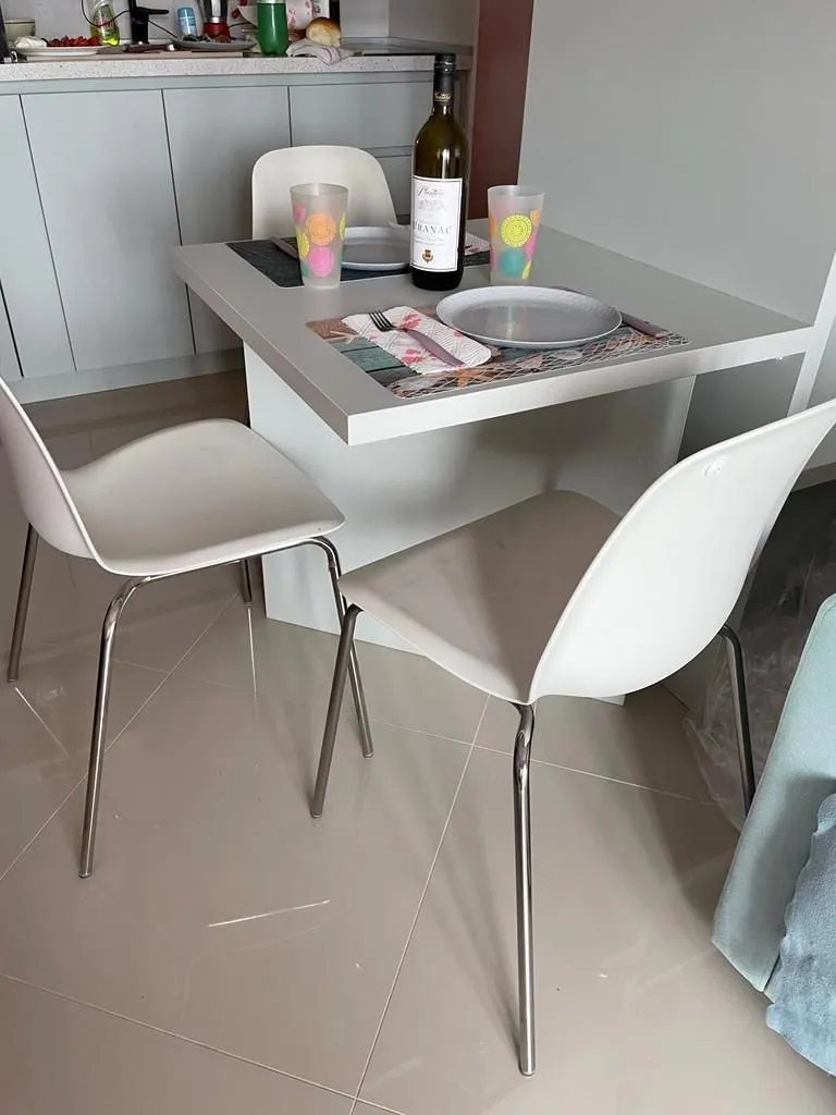 Manja trpezarija sa stolom i bijelim stolicama smještena pored kuhinje.