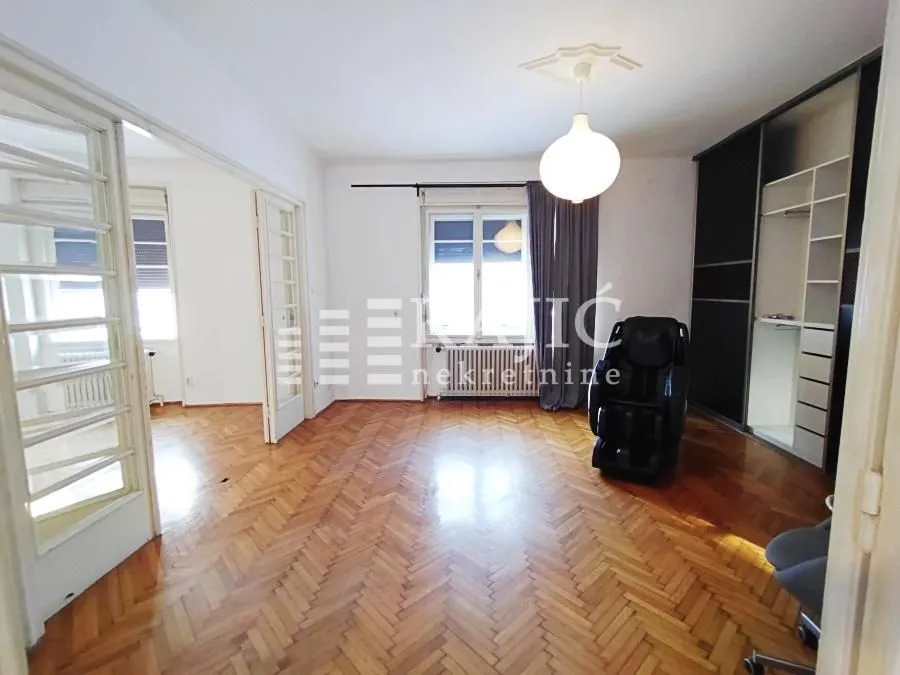 Spacious living room with parquet flooring and a wardrobe.