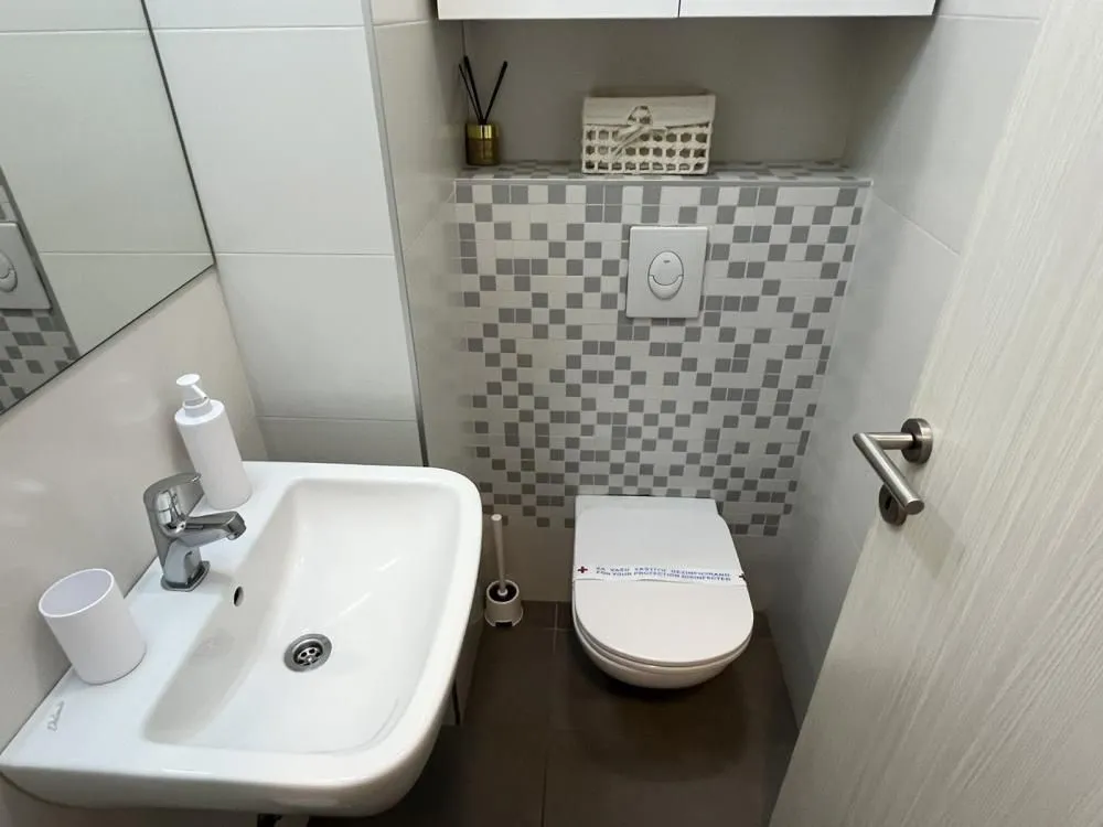 Manje kupatilo sa umivaonikom i ugradnom wc šoljom.
