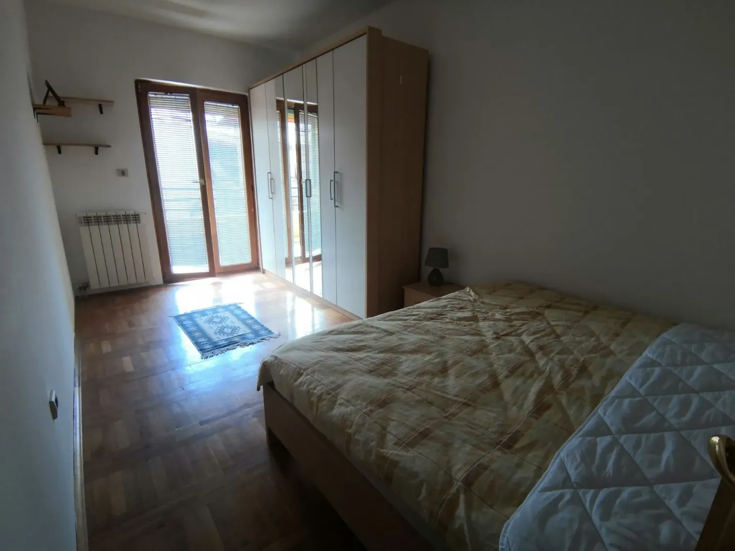 Jednostavna spavaća soba sa velikim ormarom i bračnim krevetom.