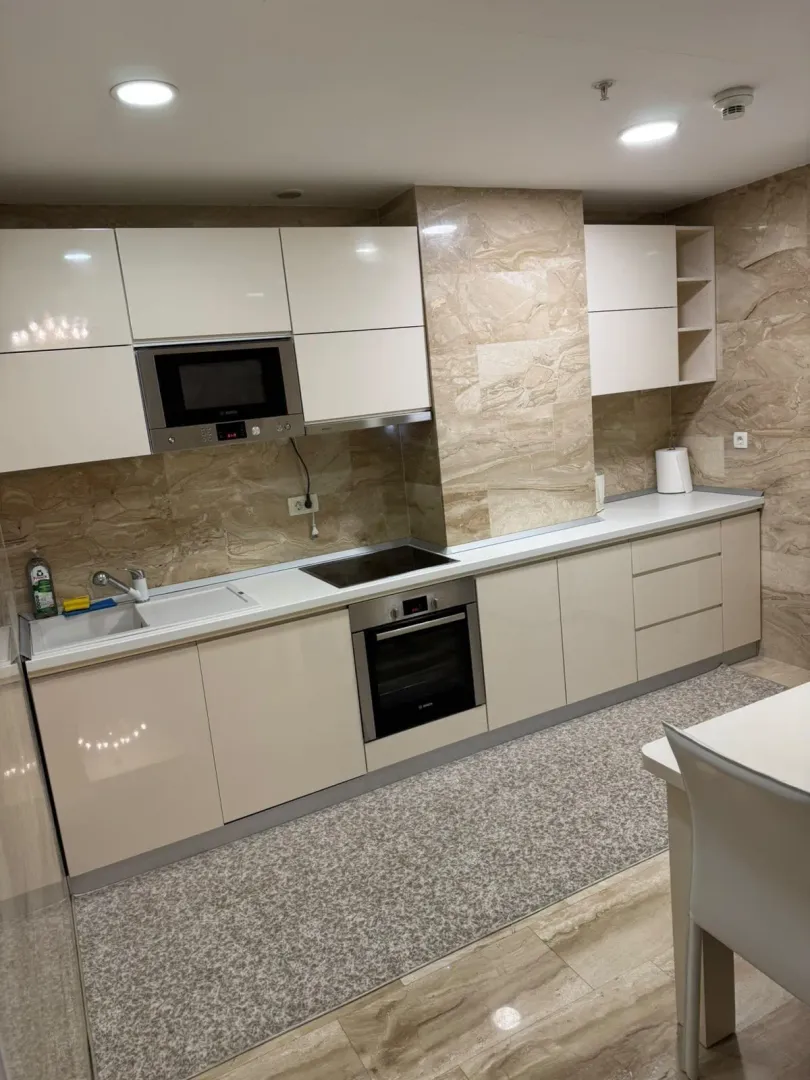 Modern kitchen with built-in appliances and glossy white cabinets.