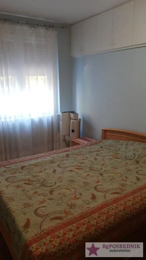 Spavaća soba sa bračnim krevetom i prozorom sa zavesama.
