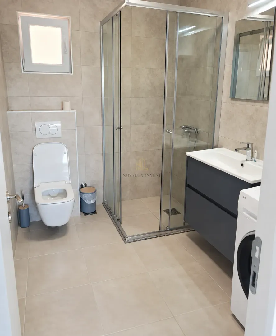 Modern bathroom with a shower cabin, washbasin, and toilet.
