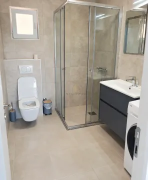 Modern bathroom with a shower cabin, washbasin, and toilet. - image 4