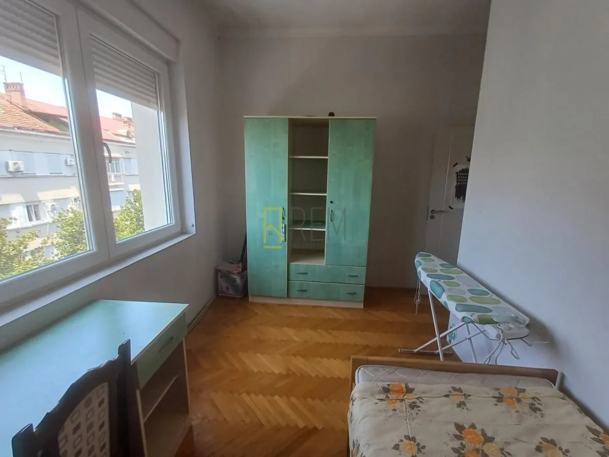 Namještena spavaća soba sa ormarom i radnim stolom.