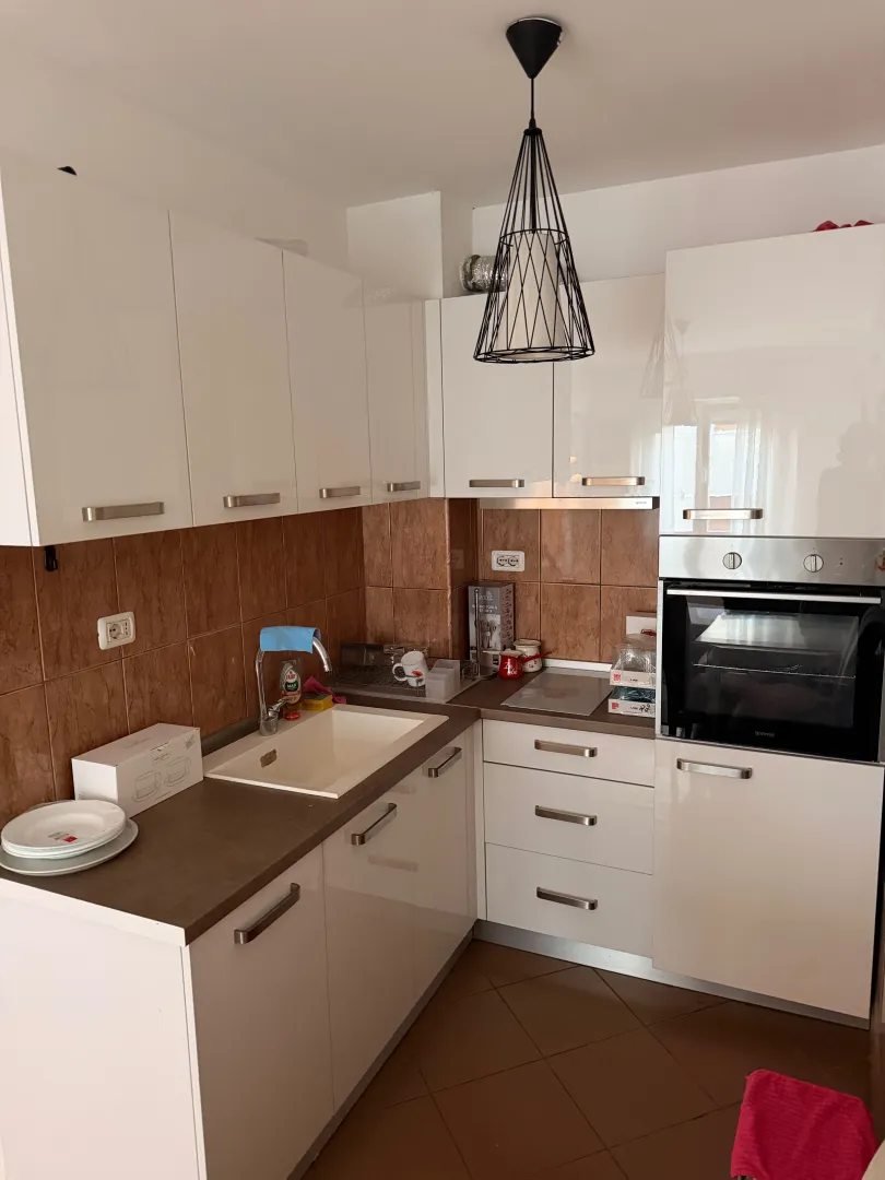 Modern white kitchen with built-in oven and sink.