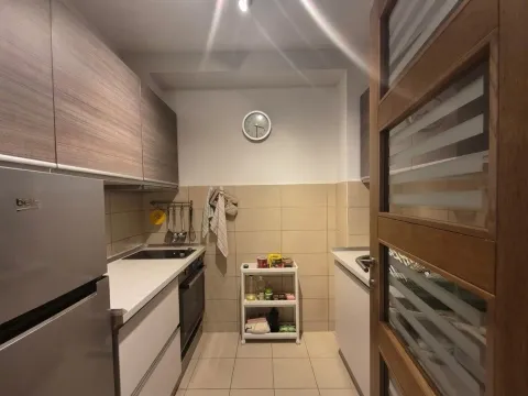 Small kitchen with wooden cabinets and built-in appliances. - image 6